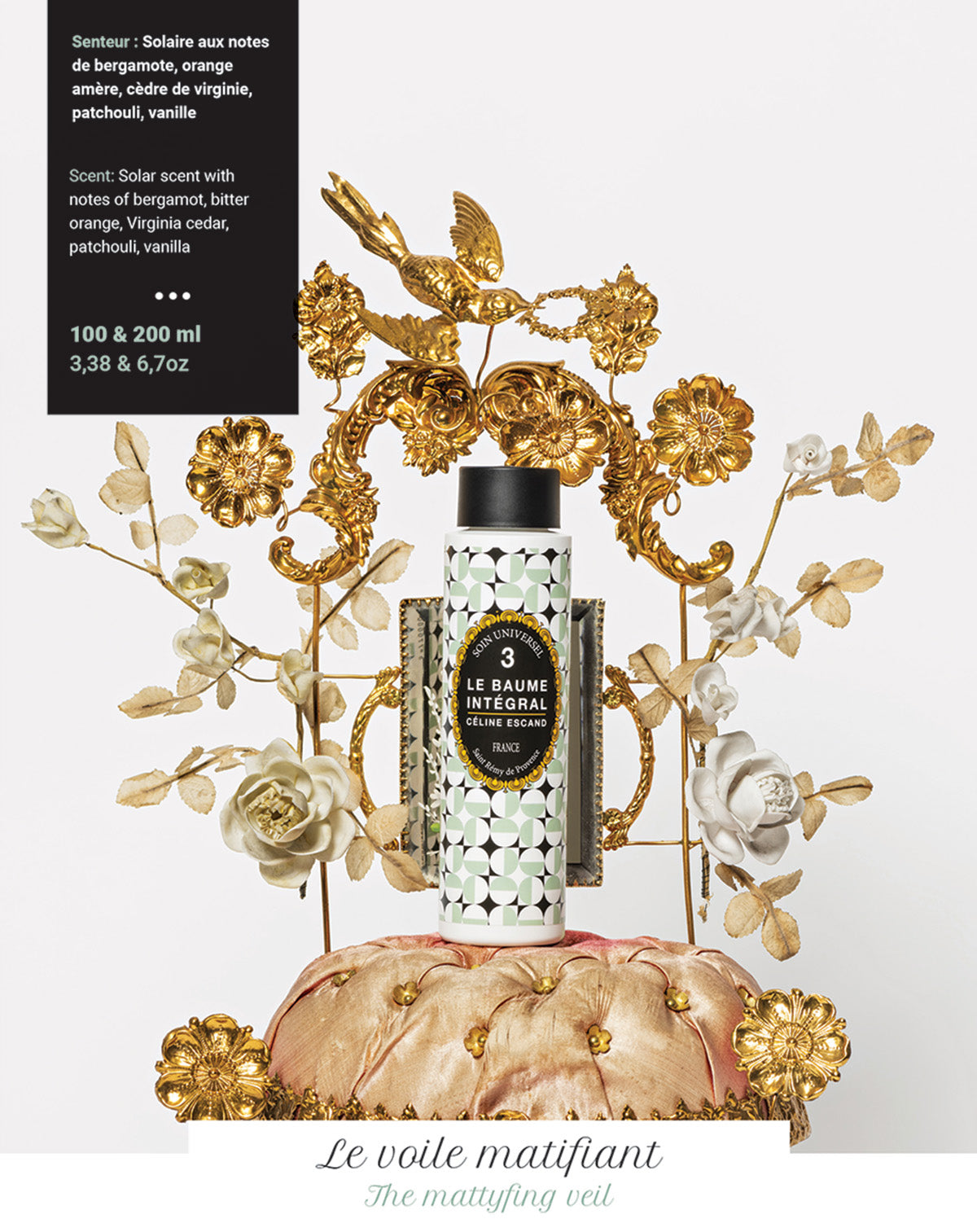 Flacon n°3 du Baume Intégral Céline Escand, soin universel bio au parfum solaire de bergamote, orange amère, cèdre de Virginie, patchouli et vanille, présenté sur fond orné de fleurs et d’oiseaux dorés.