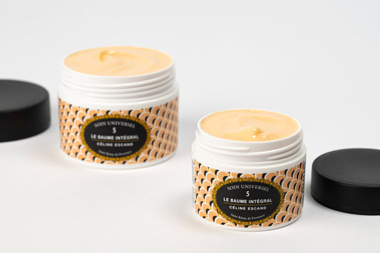 Deux pots ouverts du Baume Intégral n°5 Soin Universel de Céline Escand, révélant la texture crémeuse couleur beige naturelle, couvercles noirs posés à côté